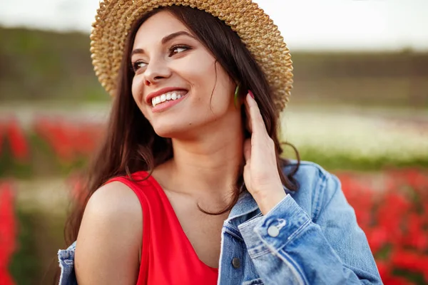 Glada ung kvinna står på blomma fält och tittar bort — Stockfoto