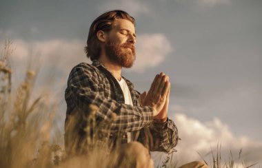 Yetişkin adam yaz tarlasında meditasyon yapıyor.