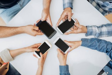 Tanımlanamayan arkadaşlar masanın üzerinde akıllı telefon kullanıyor.