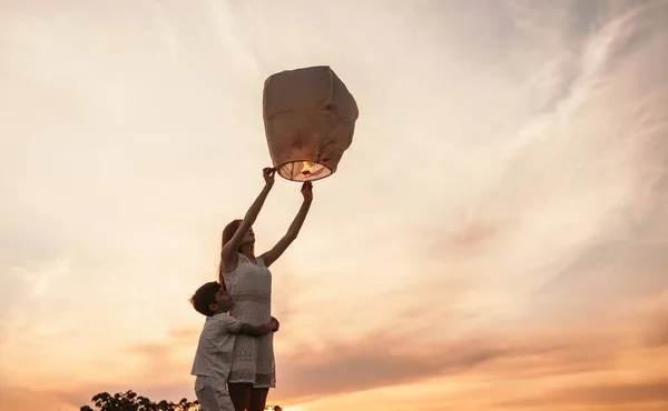 เด็กสาววัยรุ่นกับน้องชายตัวเล็ก ปล่อยโคมไฟท้องฟ้า — ภาพถ่ายสต็อก