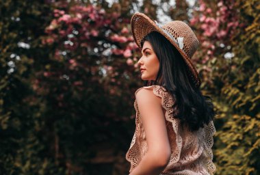 Çiçek açan bahçede yürüyen zarif bir kadın.