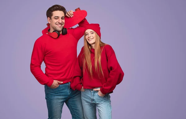 Alegre jovem casal ativo com skate olhando para a câmera — Fotografia de Stock