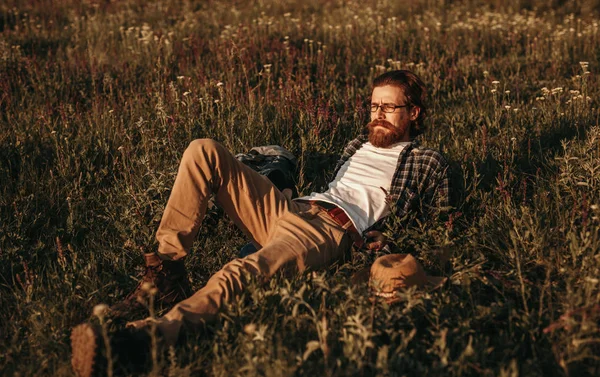 Hippi adam çimlere uzanıyor ve yaz gününün tadını çıkarıyor. — Stok fotoğraf