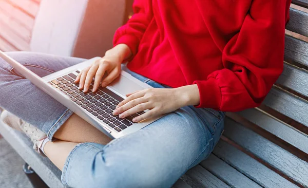 Jovem mulher sentada no banco e trabalhando no laptop — Fotografia de Stock