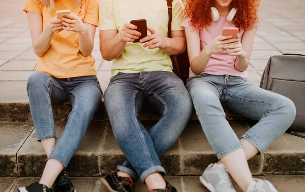 Jugendliche sitzen zusammen und nutzen Smartphones — Stockfoto