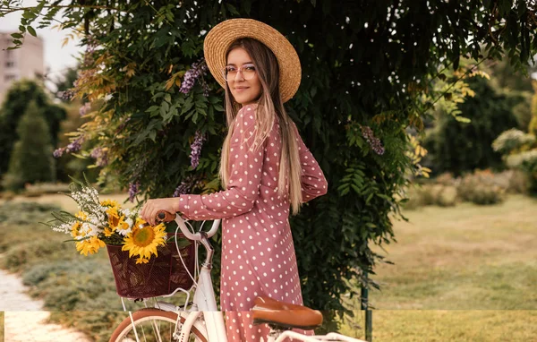 Mulher na moda com bicicleta de pé perto da árvore florescente — Fotografia de Stock
