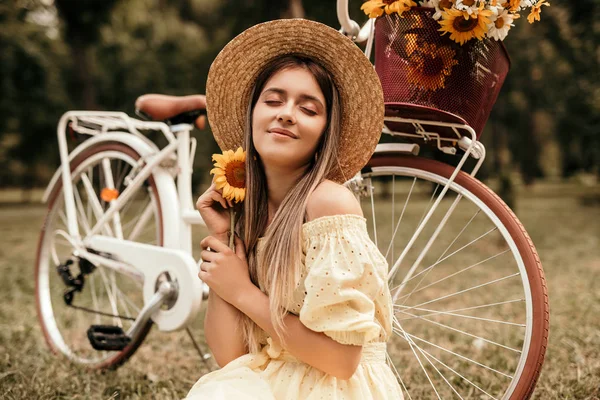 Nöjd kvinna med solros sittande nära retro cykel — Stockfoto