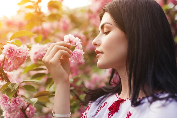 Ung kvinna luktar sakura blommor — Stockfoto