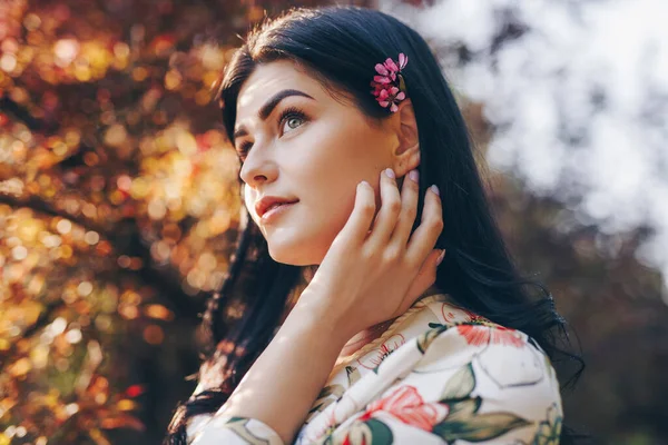Мрійлива жінка з квіткою у волоссі в парку — стокове фото