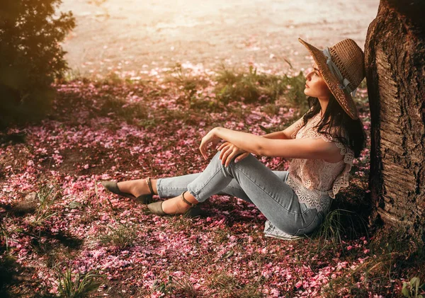Мечтательная женщина, отдыхающая у дерева в весеннем парке — стоковое фото