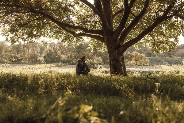 Onherkenbare wandelaar rustend onder een boom in de natuur — Stockfoto