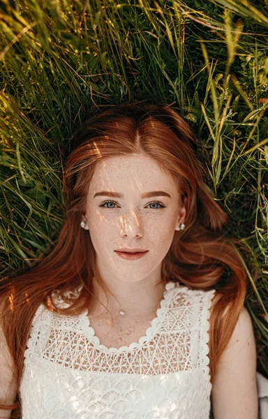Ginger female lying on green grass — 스톡 사진