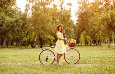 Bisikletli şık bir kadın parkta dinleniyor.