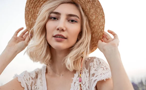 Stylish blond woman adjusting hat in nature — 스톡 사진