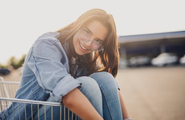 Alışveriş arabasındaki neşeli genç bayan.
