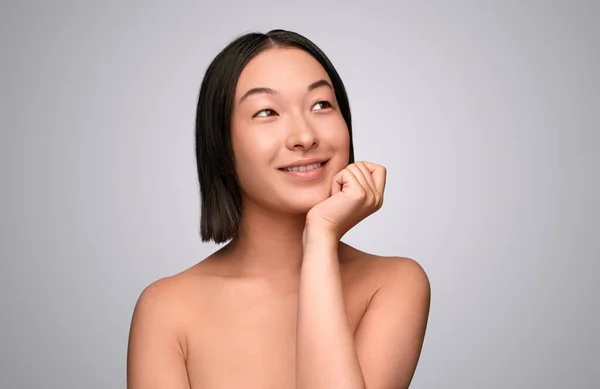 Donna cinese sognante che pensa alla cura della pelle — Foto Stock