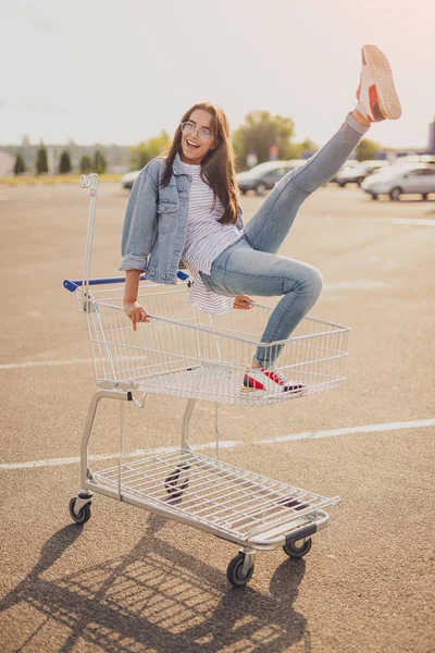 Excited young lady having fun on shopping trolley — 스톡 사진