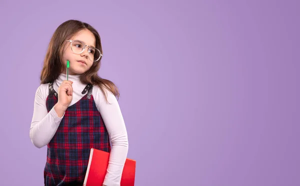 Pensive schoolmeisje met pen en boek — Stockfoto