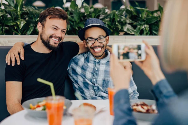 Crop woman taking photo of male friends — Stockfoto