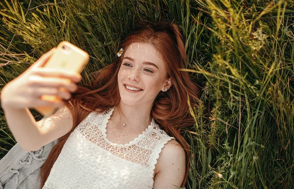 Wanita muda yang bahagia mengambil selfie di rumput — Stok Foto
