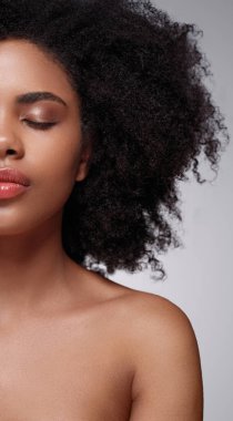 Yumuşak makyajlı ve çıplak omuzlu genç bir Afro-Amerikan kadın model.