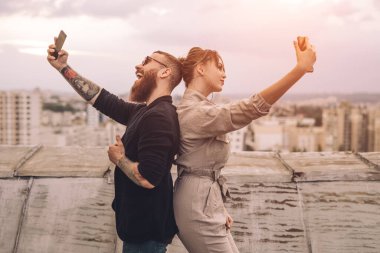 Çatıda selfie çeken genç bir çift.