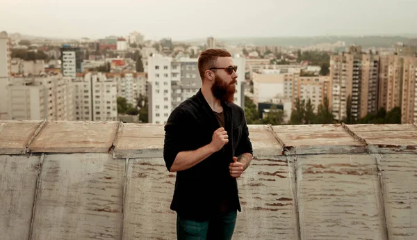 Allvarlig hipster man står på taket i staden — Stockfoto