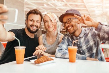 İyimser çeşitli arkadaşlar öğle yemeği sırasında selfie çekiyorlar.