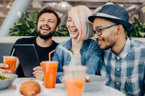 Multiraciala vänner bläddrar surfplatta och skrattar efter jobbet — Stockfoto