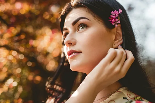 Verträumte Dame justiert Haare im Garten — Stockfoto