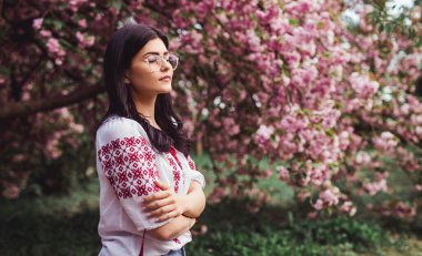 Authentic woman relaxing near blooming tree