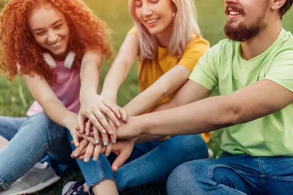 Fellow students stacking hands in park — 图库照片