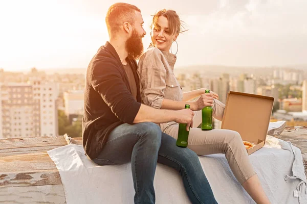 Cheerful couple with beer dating on rooftop — Stockfoto