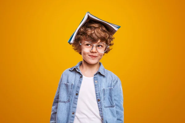 Curious pupil with textbook on head