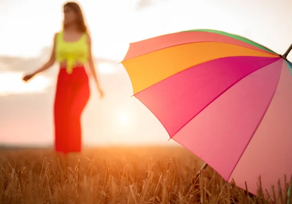 Bunter Regenschirm auf Feld neben Frau — Stockfoto