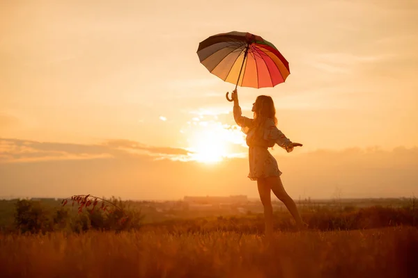 Молода жінка з парасолькою танцює під час заходу сонця — стокове фото