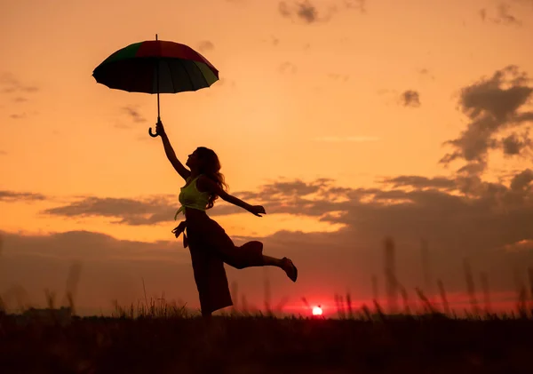 Dama delgada con paraguas divirtiéndose al atardecer — Foto de Stock