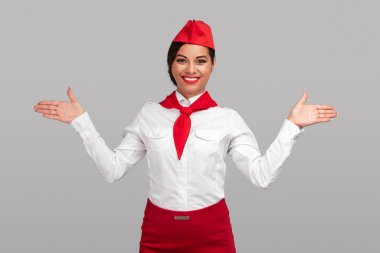 Cheerful adult air hostess showing way to emergency exit