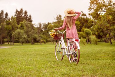 Anonymous woman with bicycle enjoying sunny day in park