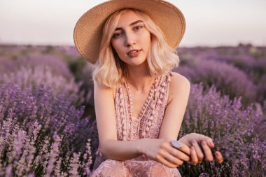 Magnificent young alluring woman with violet wildflowers in field