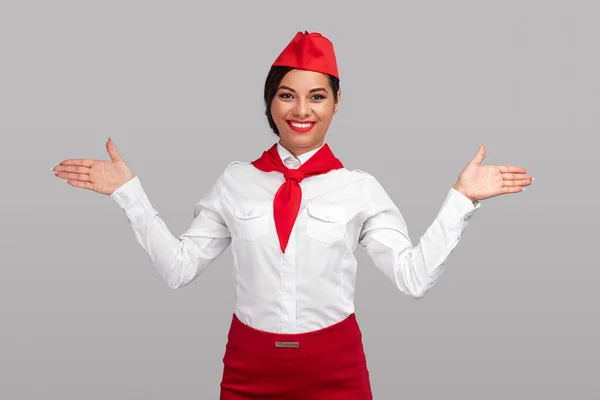 Cheerful adult air hostess showing way to emergency exit — Stockfoto