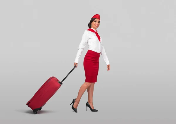 Confident adult air hostess in colorful uniform with bright vivid suitcase — Φωτογραφία Αρχείου