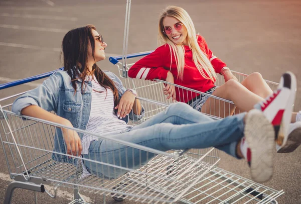 Happy friends in shopping trolleys talking with each other — 图库照片