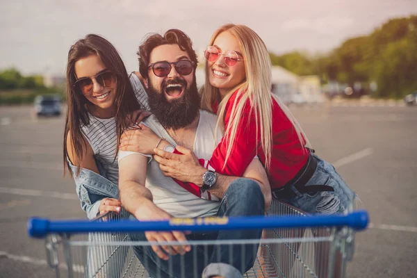 Amigos felizes abraçando perto do carrinho de compras — Fotografia de Stock