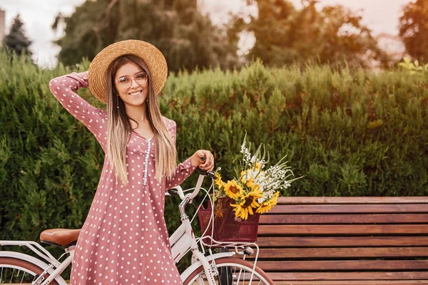 Mulher alegre com bicicleta perto do banco — Fotografia de Stock