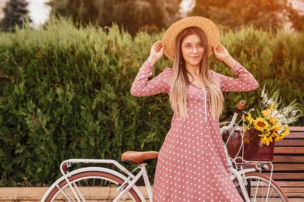 Mulher na moda ajustando chapéu perto de bicicleta — Fotografia de Stock