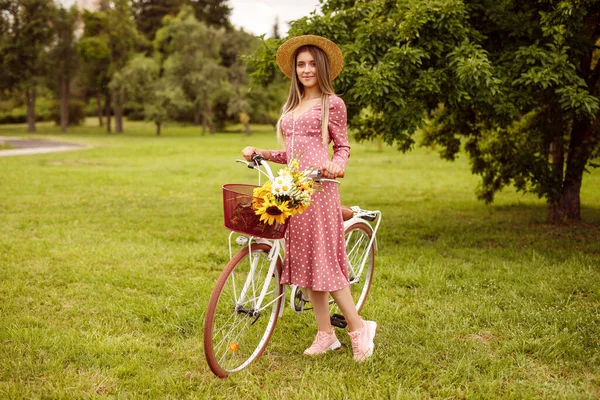 Mulher elegante com bicicleta vintage em pé no gramado do parque — Fotografia de Stock