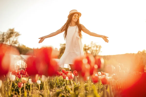 Avslappnad positiv kvinna sprider händerna promenader på blomma fält — Stockfoto
