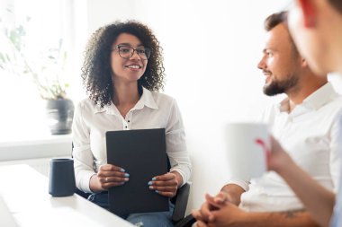 Siyahi iş kadını iş arkadaşlarıyla konuşuyor.
