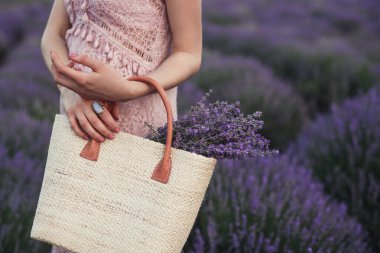 Woman with straw bag standing in lavender field